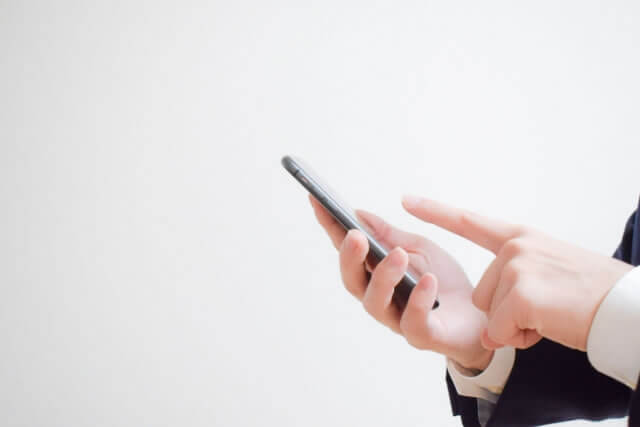 スマートフォンを手に持ち、画面を操作しながら設定を確認している様子