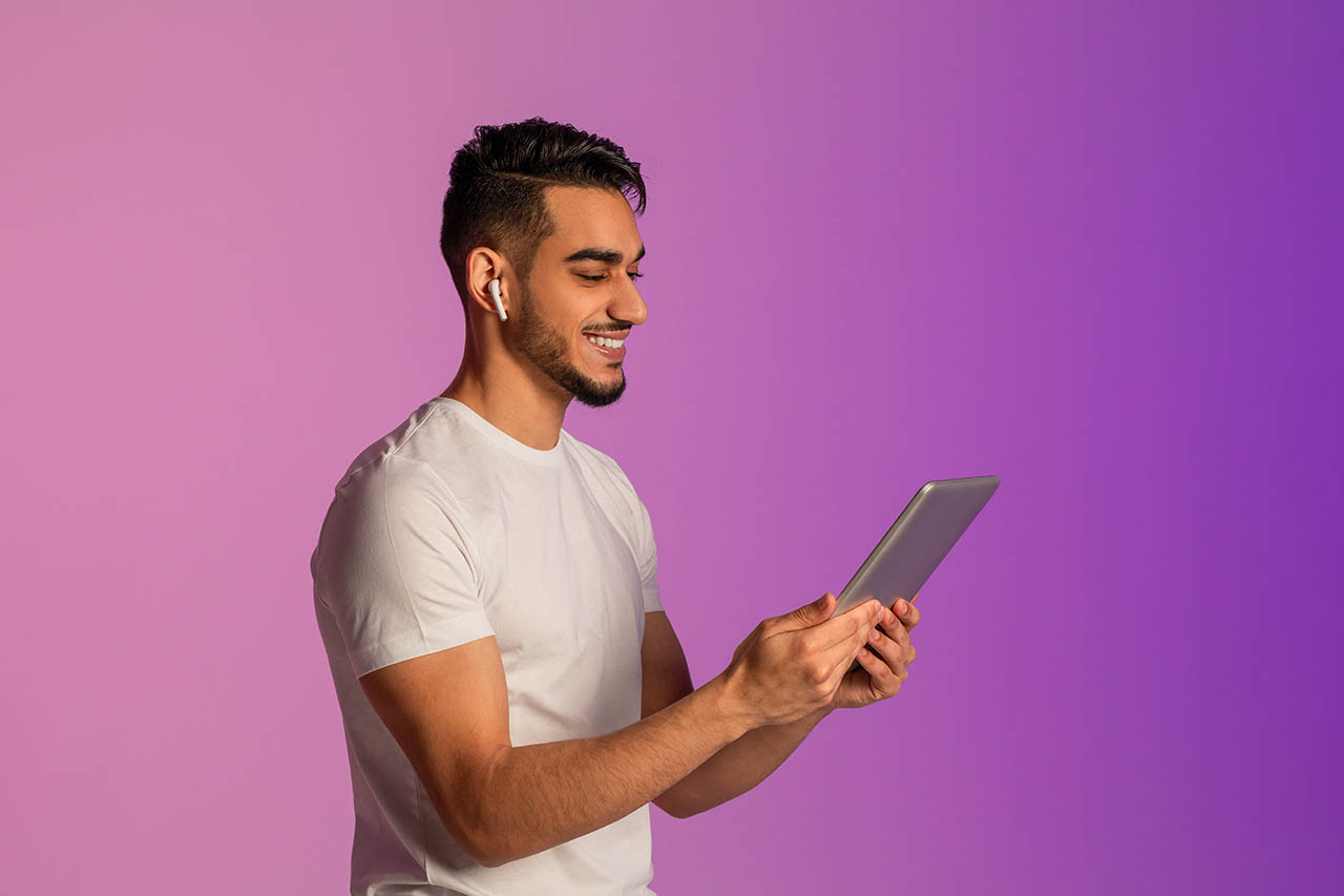 ワイヤレスイヤホンを装着してタブレットを操作する男性